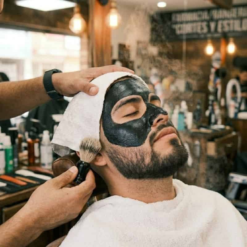 Hombre relajado con mascarilla negra durante un facial en Mineral de la Reforma